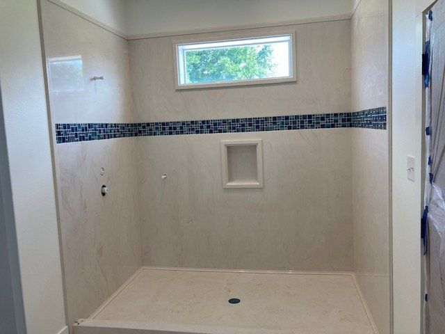 A bathroom with a walk in shower and a window.