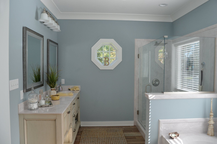 A bathroom with two sinks , two mirrors and a walk in shower.