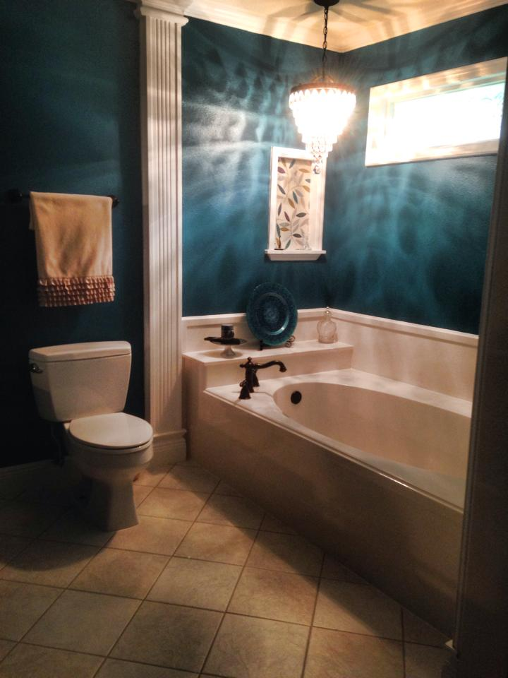 A bathroom with a toilet a tub and a chandelier