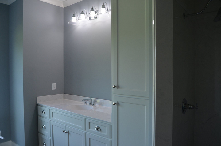 A bathroom with a sink , cabinets , and a shower.