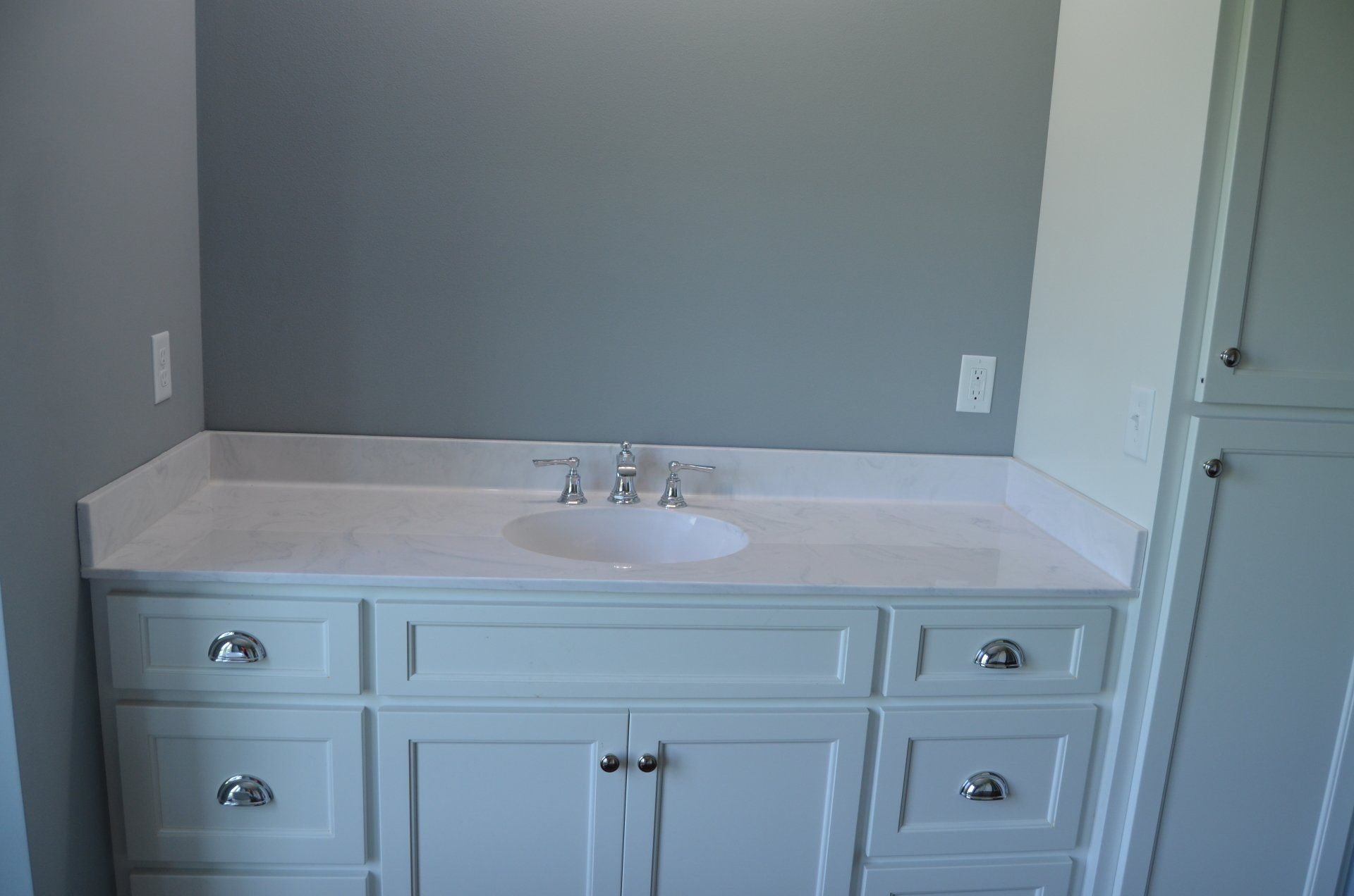 A bathroom with a sink , cabinets , drawers and a mirror.