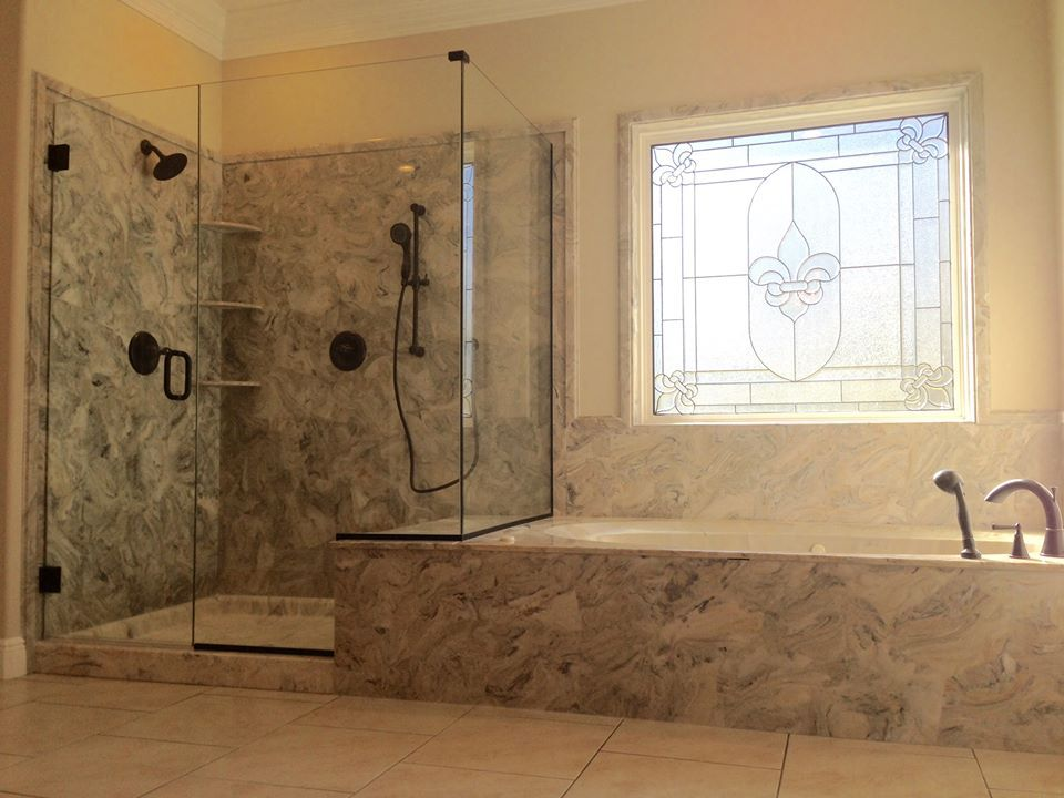 A bathroom with a walk in shower , tub , and stained glass window.