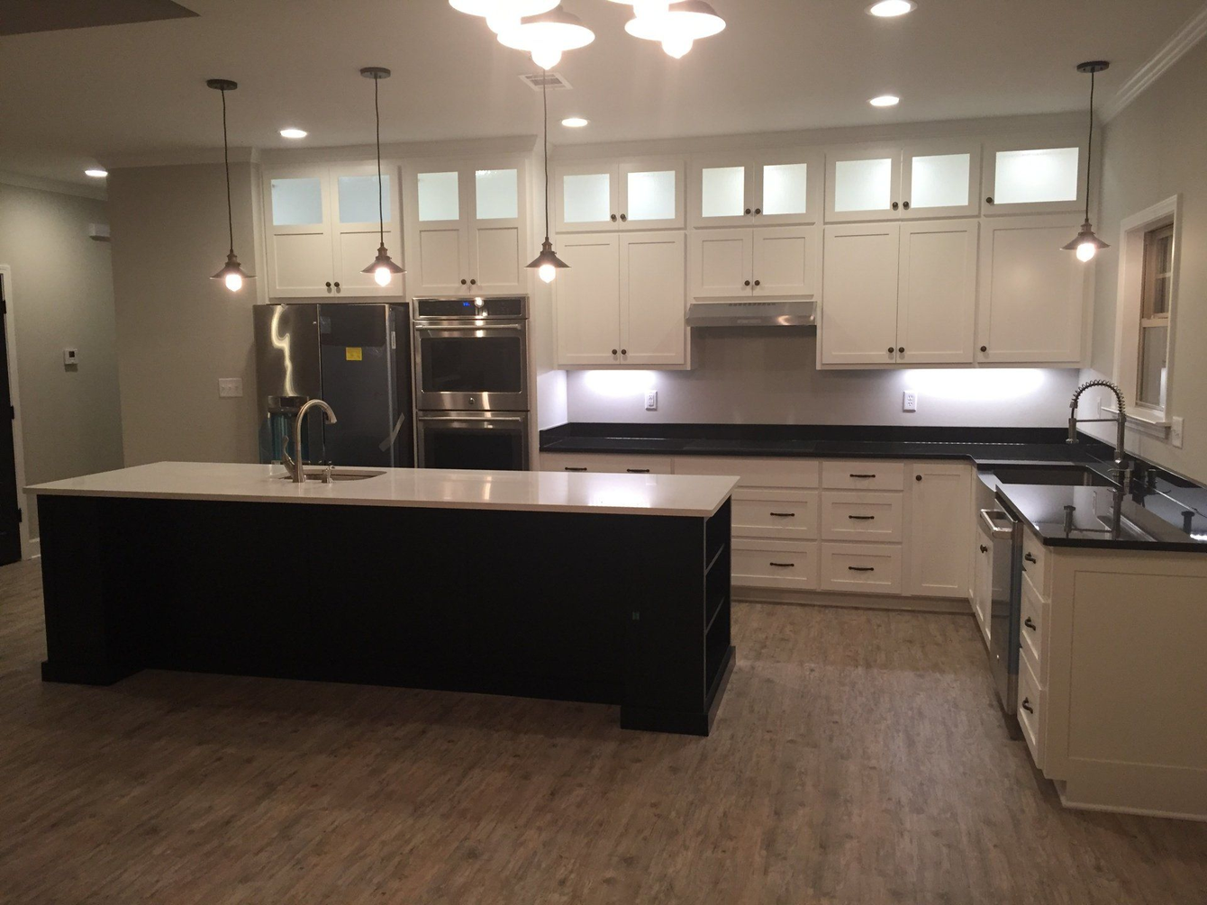 A kitchen with white cabinets and black counter tops