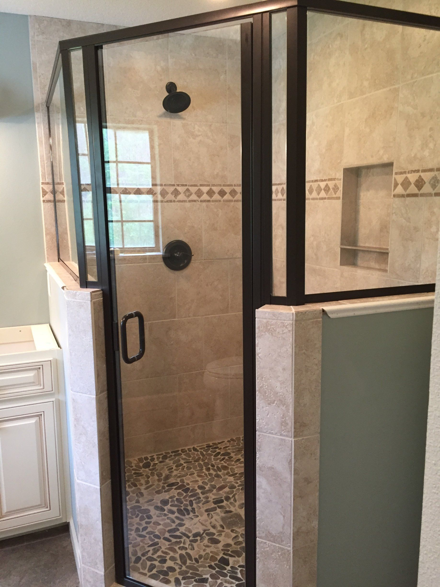 A bathroom with a walk in shower with a glass door.