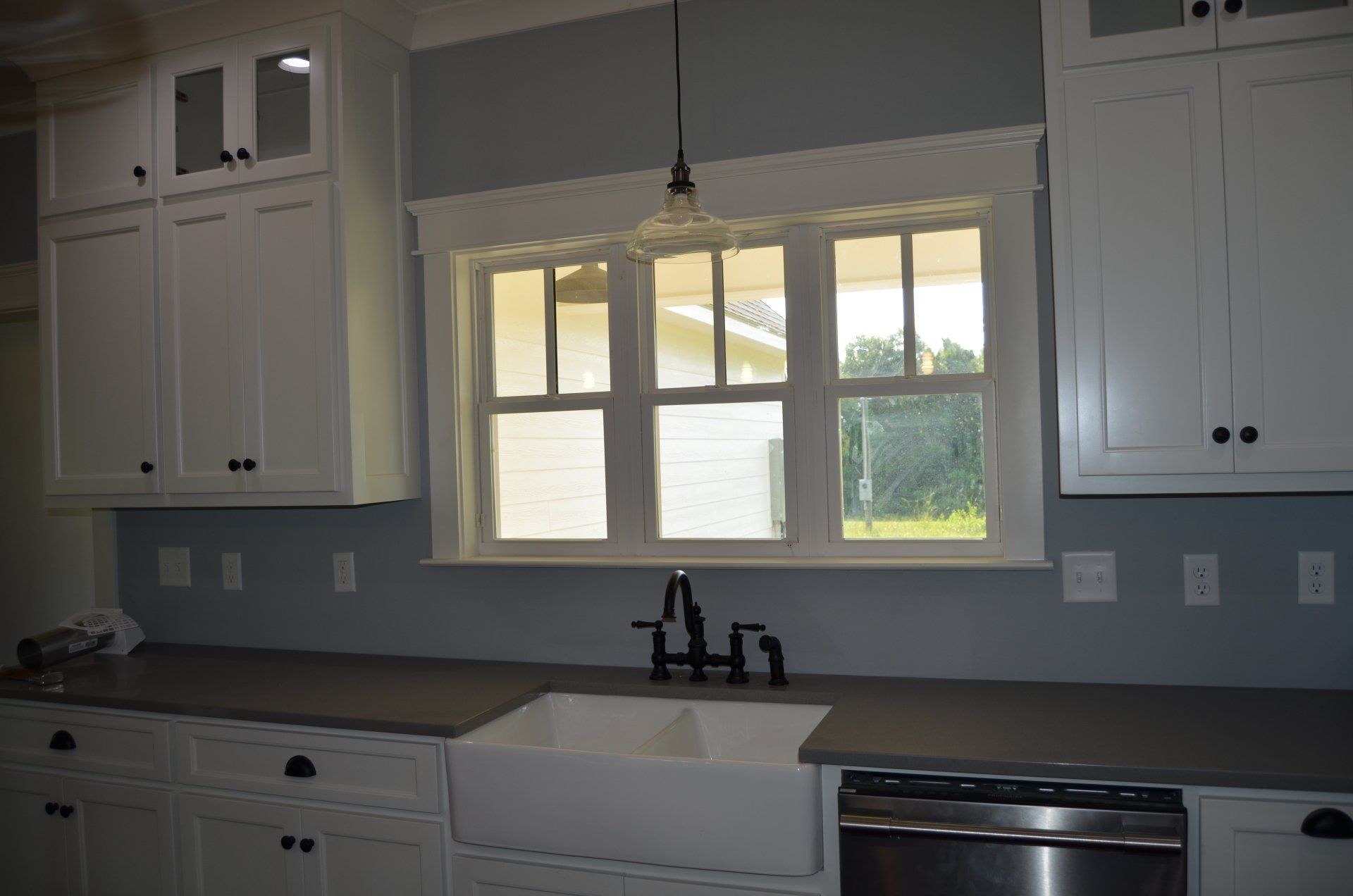 A kitchen with white cabinets a sink and a window