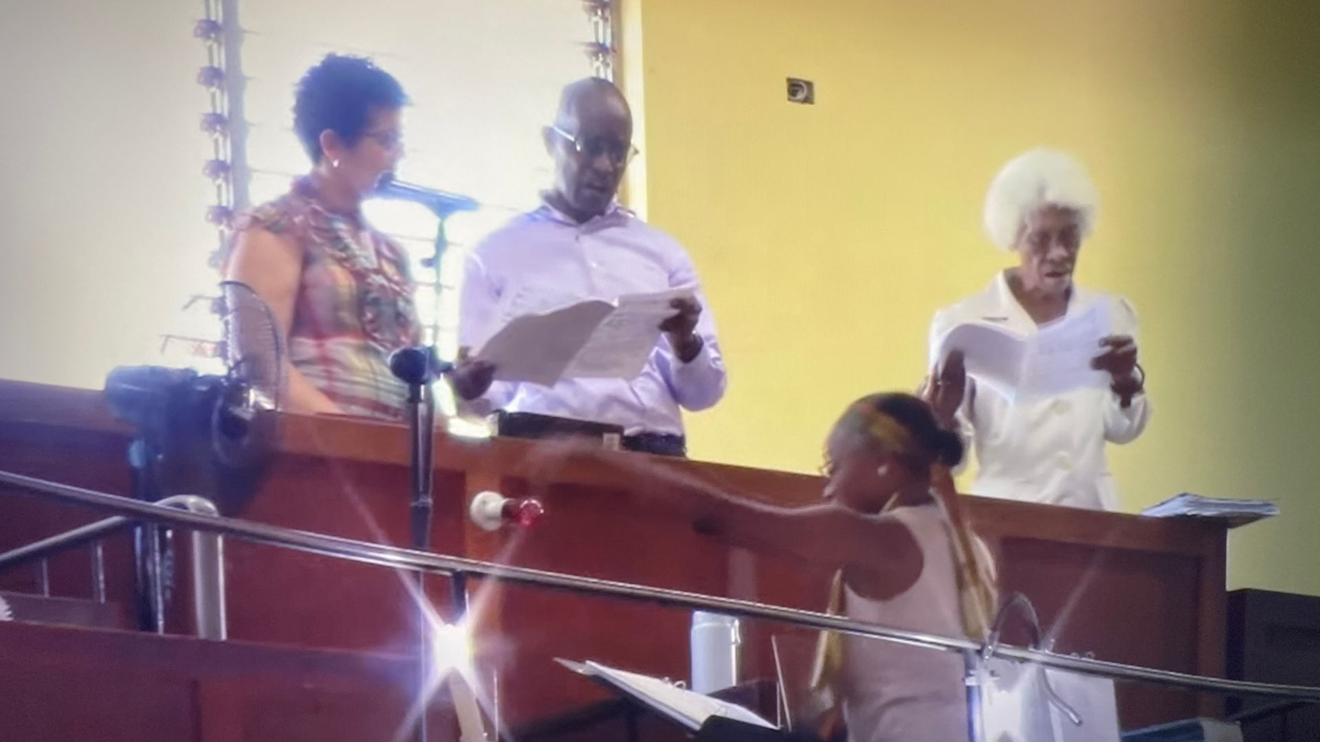 A group of people are standing in front of a microphone.