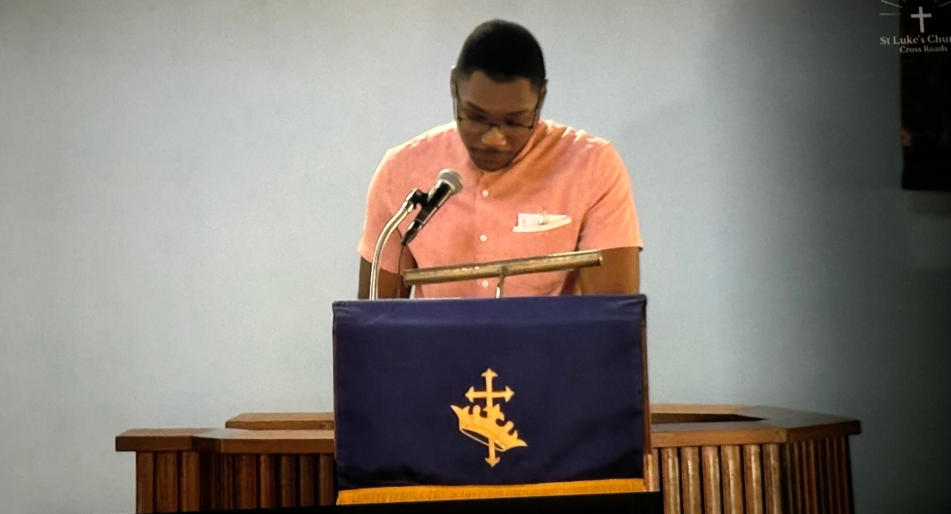 A man stands at a podium with a cross on it
