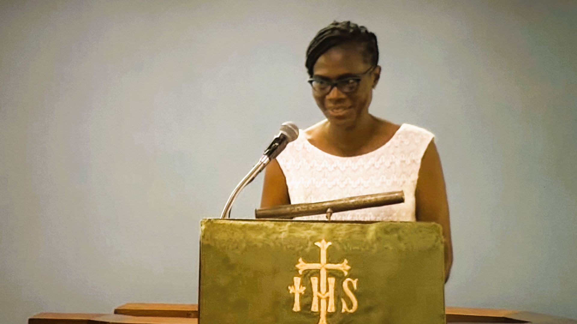A woman is standing at a podium speaking into a microphone.