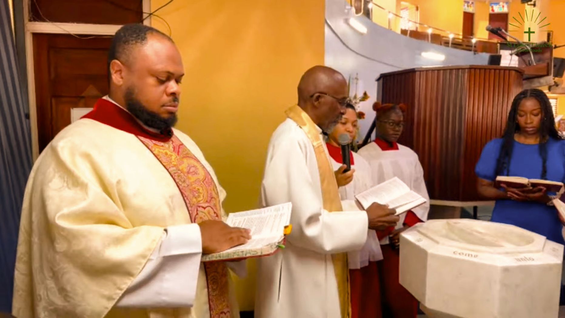 A group of priests are standing around a baptismal font in a church.