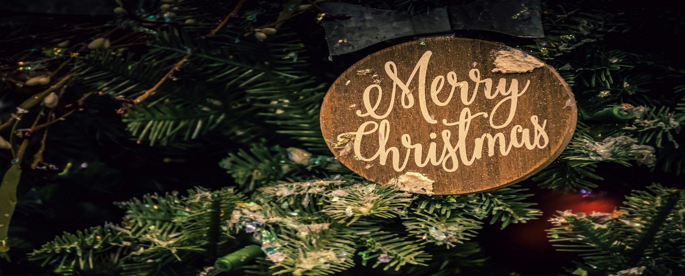 Wooden ornament on a Christmas tree that says Merry Christmas.