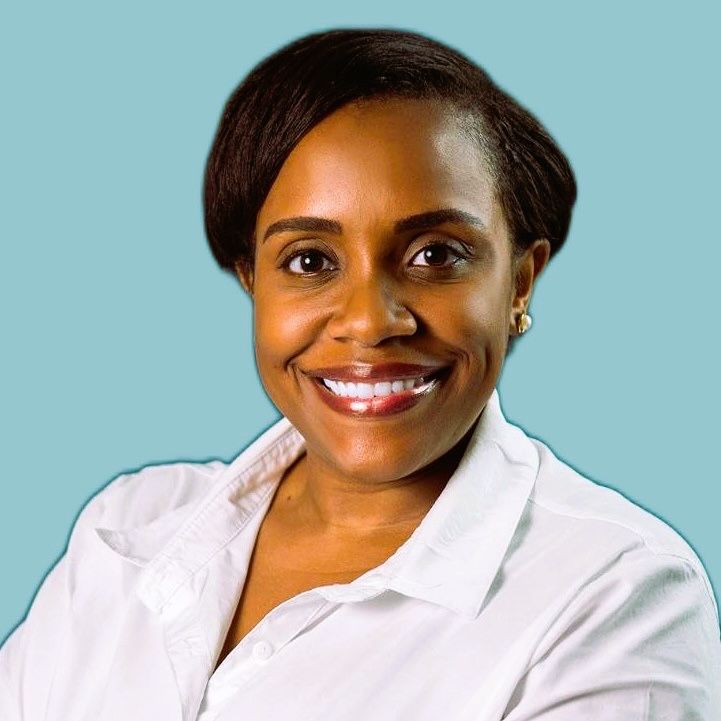 A woman in a white shirt is smiling with her arms crossed.