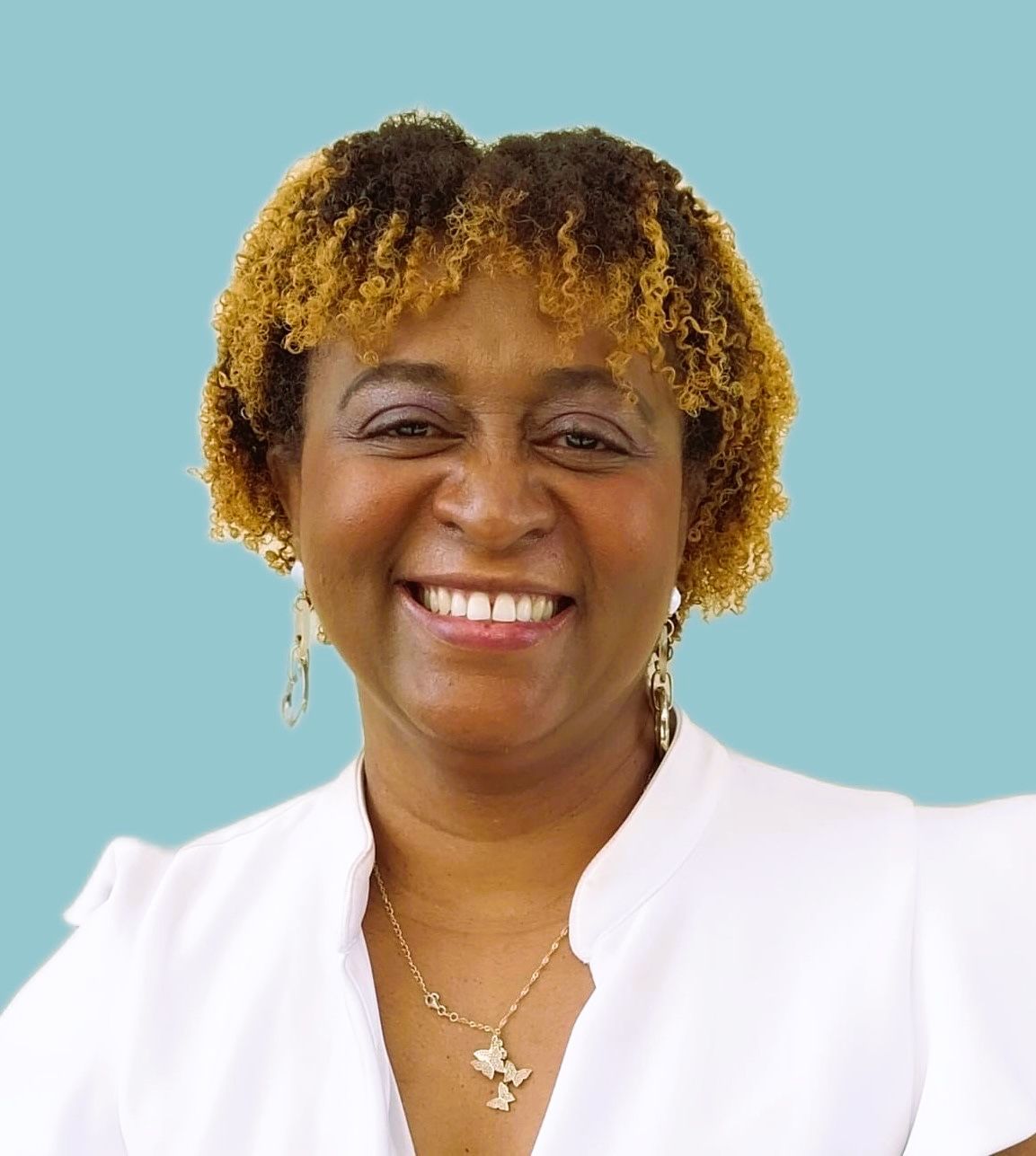 A woman wearing a white shirt and a necklace is smiling