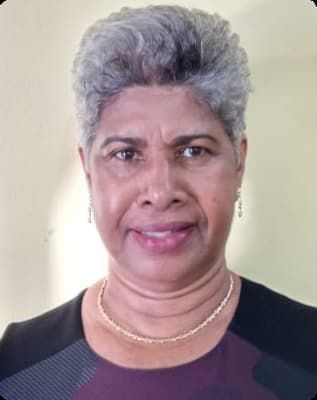 A woman with gray hair and a necklace is smiling for the camera.