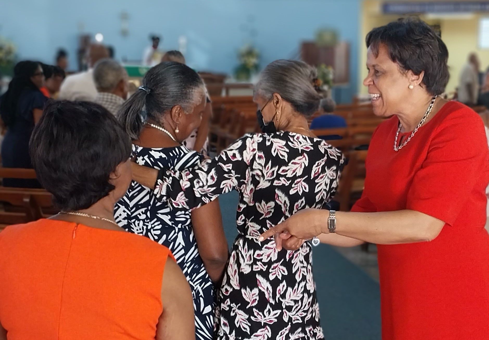 A woman in a red shirt is talking to two other women