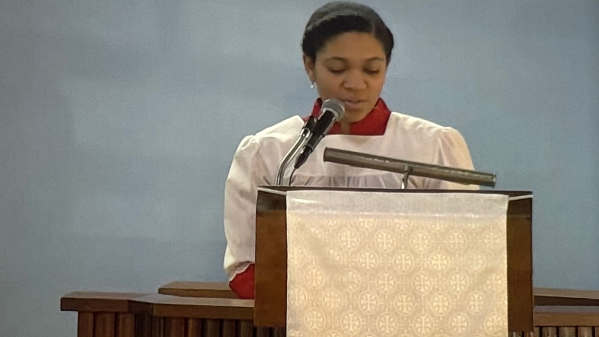 A woman is standing at a podium speaking into a microphone.