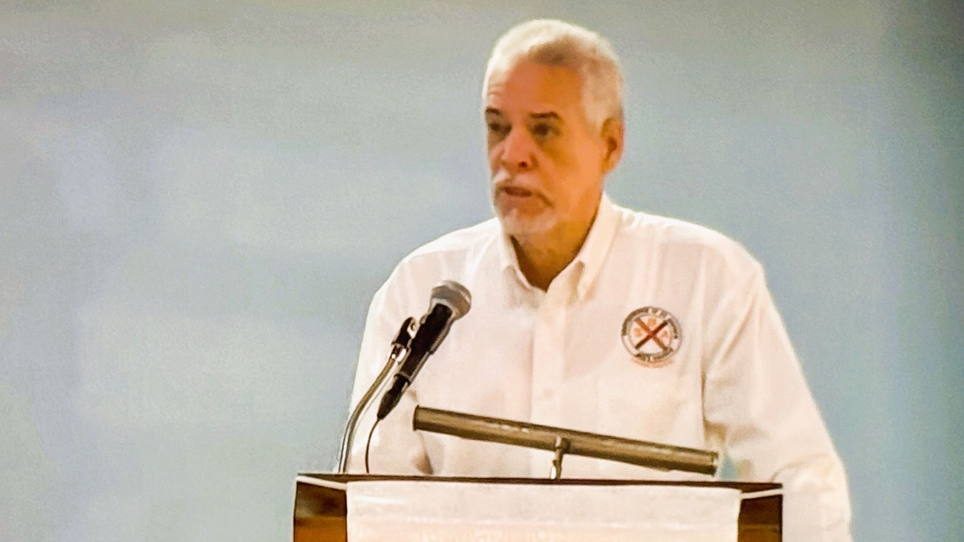 A man is standing at a podium speaking into a microphone.