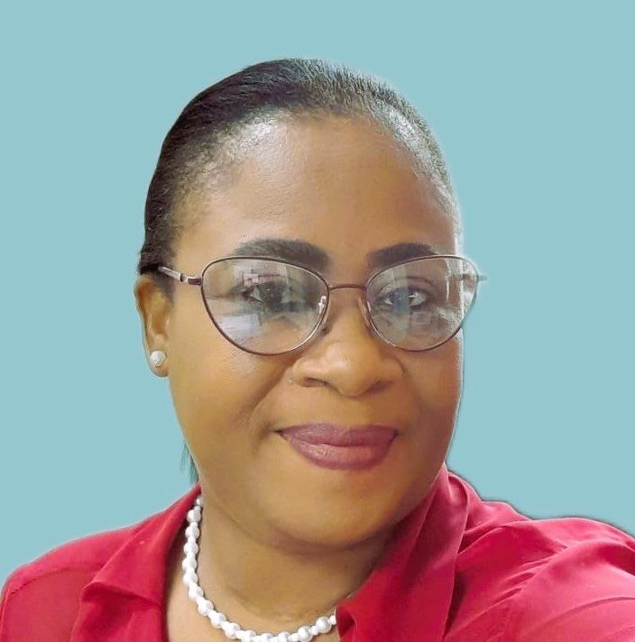 A woman wearing glasses and a red shirt is smiling for the camera.