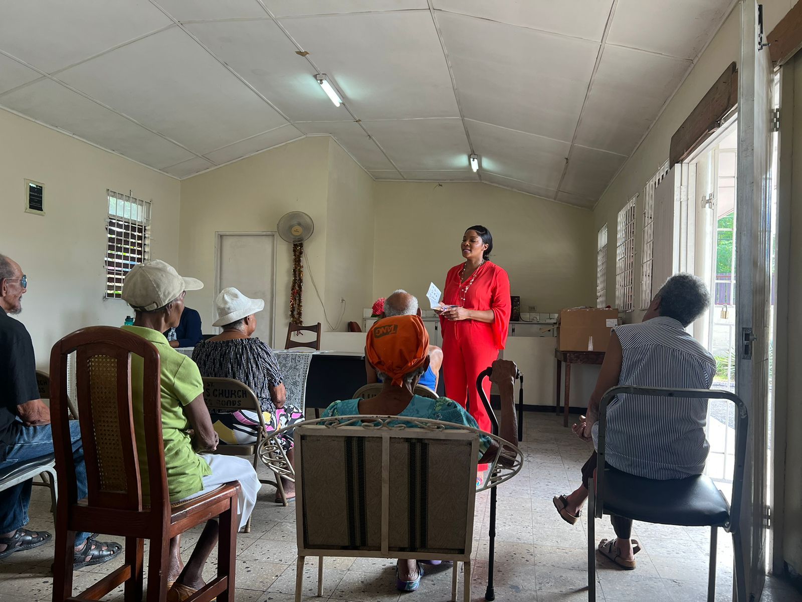 A woman is standing in front of a group of people sitting in chairs.