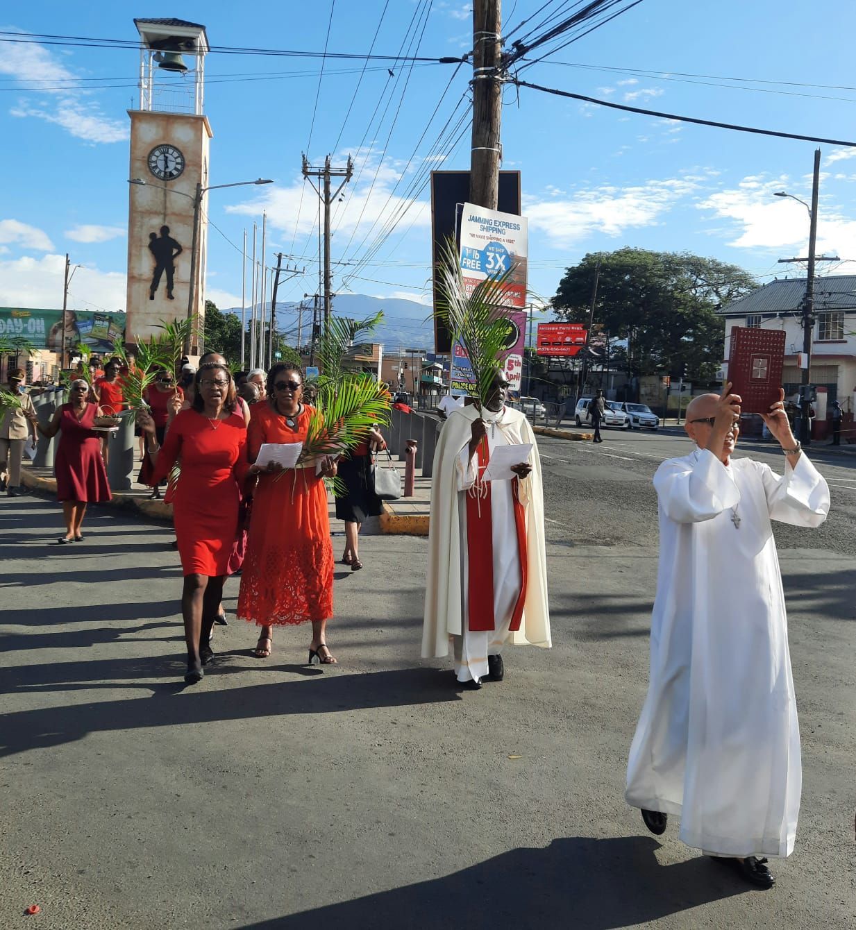 A Church group of people walking down a street with a clock tower in the background