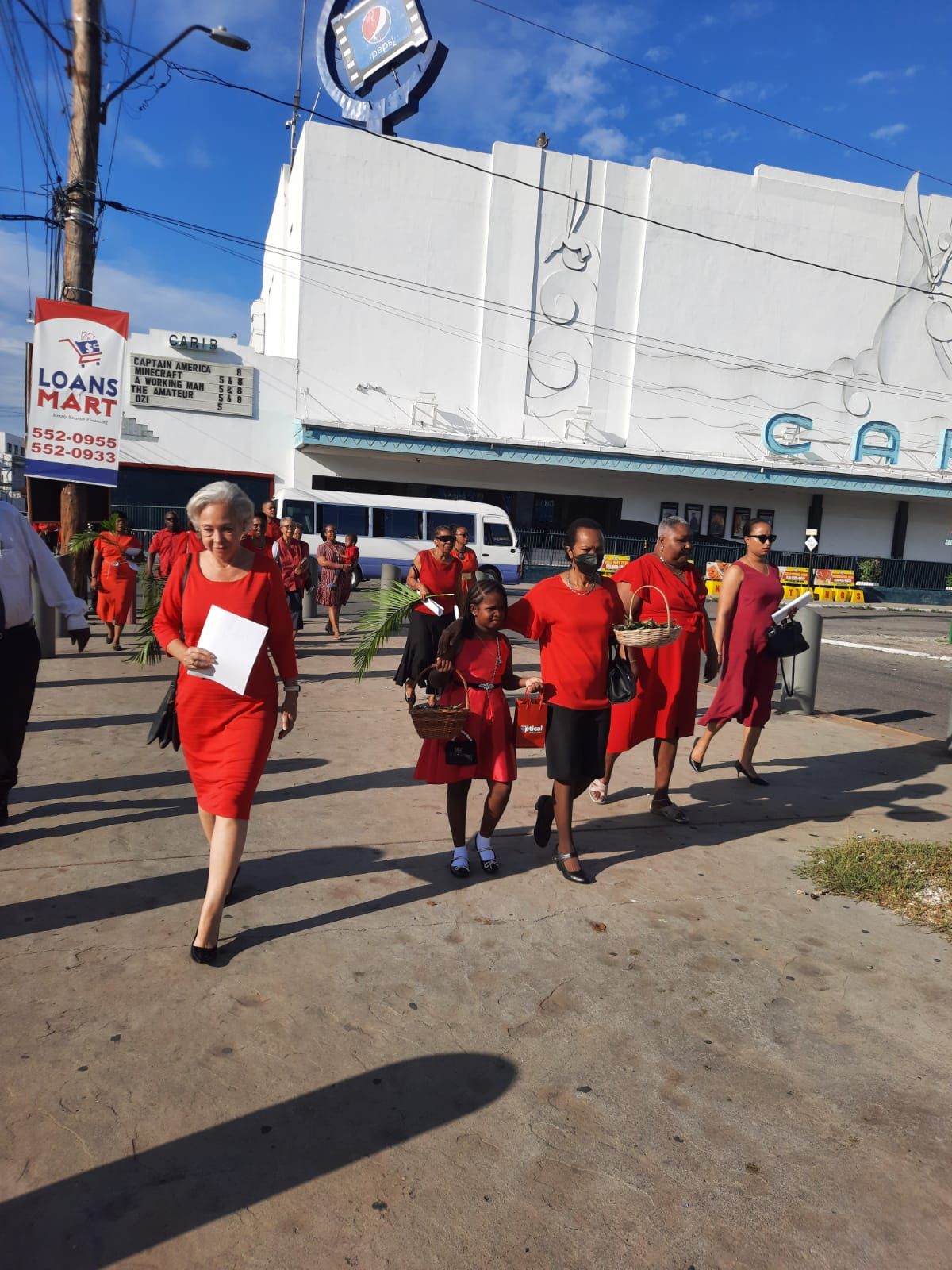 A group of people walking down a street with palms in hand for palm Sunday.