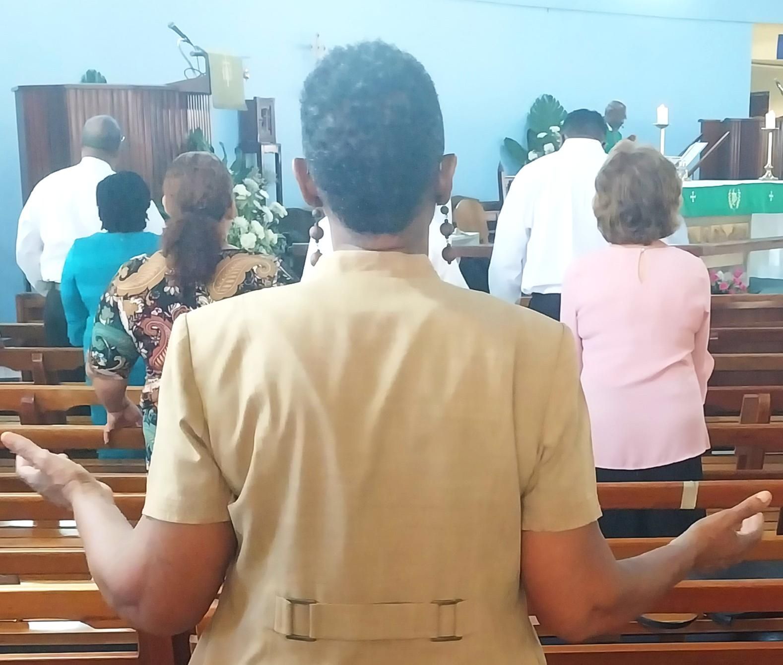 A group of people are sitting in a church with their arms outstretched