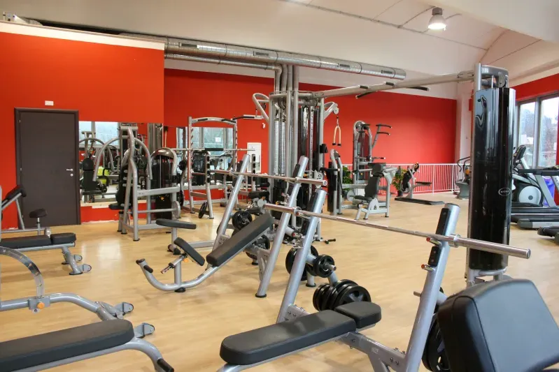 Una palestra con un sacco di attrezzature e un muro rosso