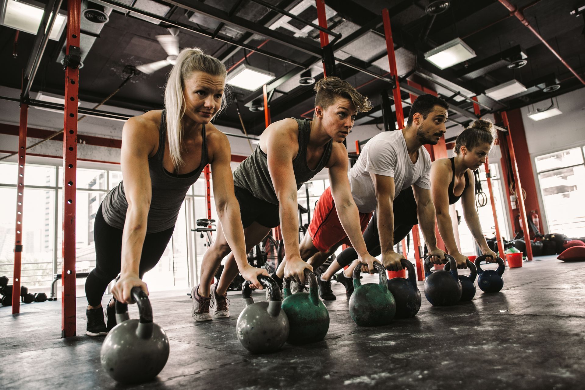 Un gruppo di persone sta facendo flessioni con i kettlebell in una palestra.