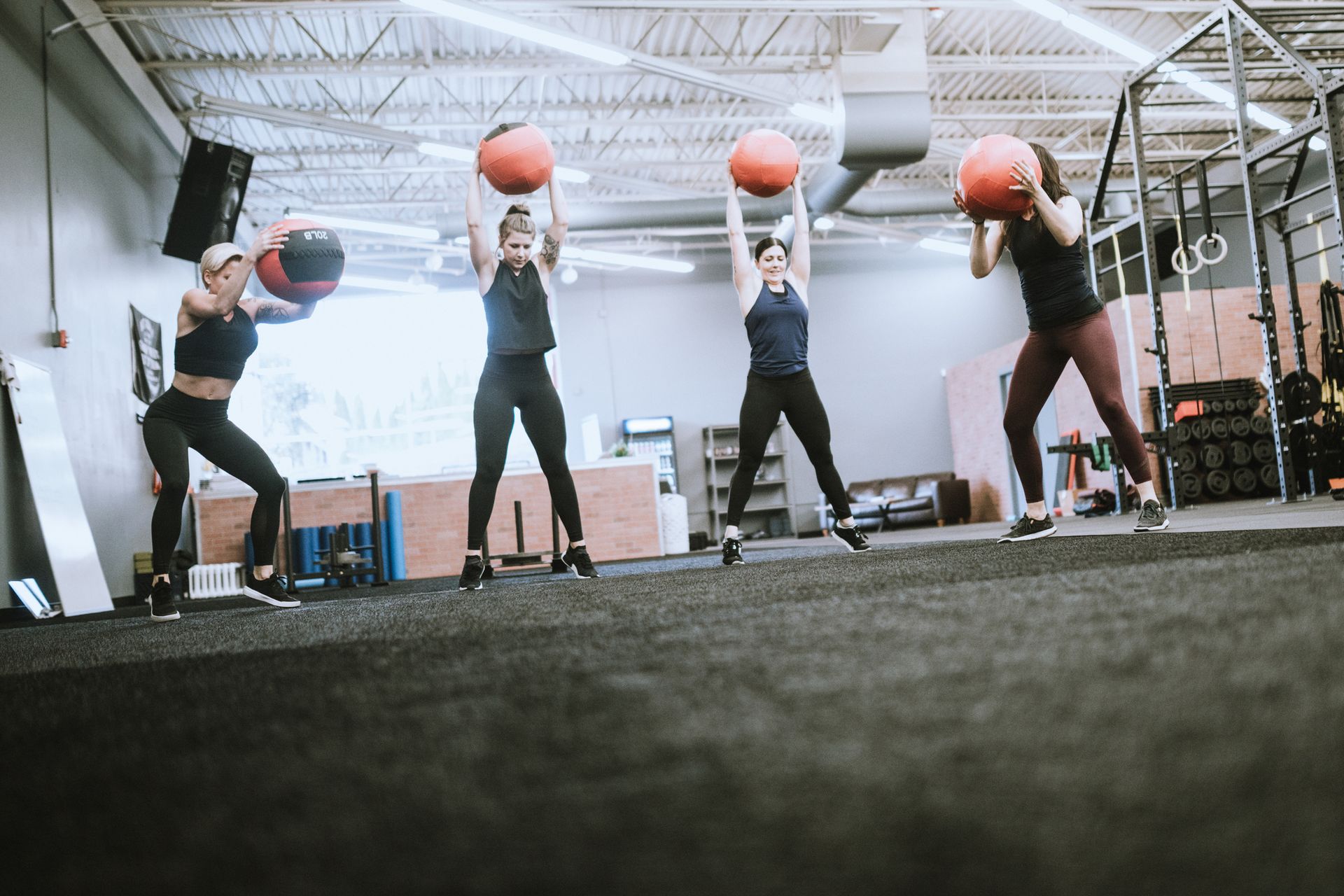 Un gruppo di donne sta facendo esercizi con le palle mediche in una palestra.