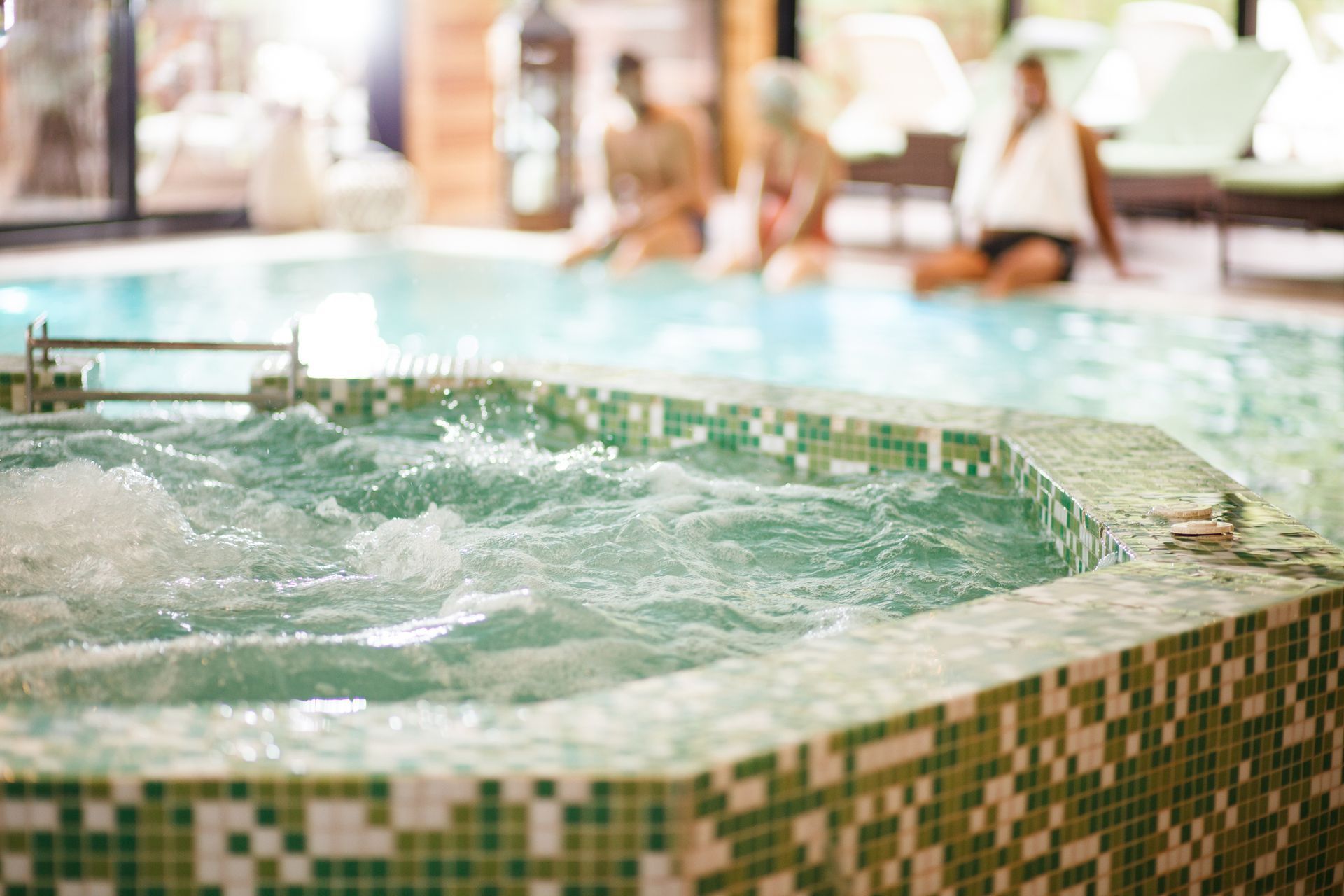 Una donna è seduta nella jacuzzi di una piscina.