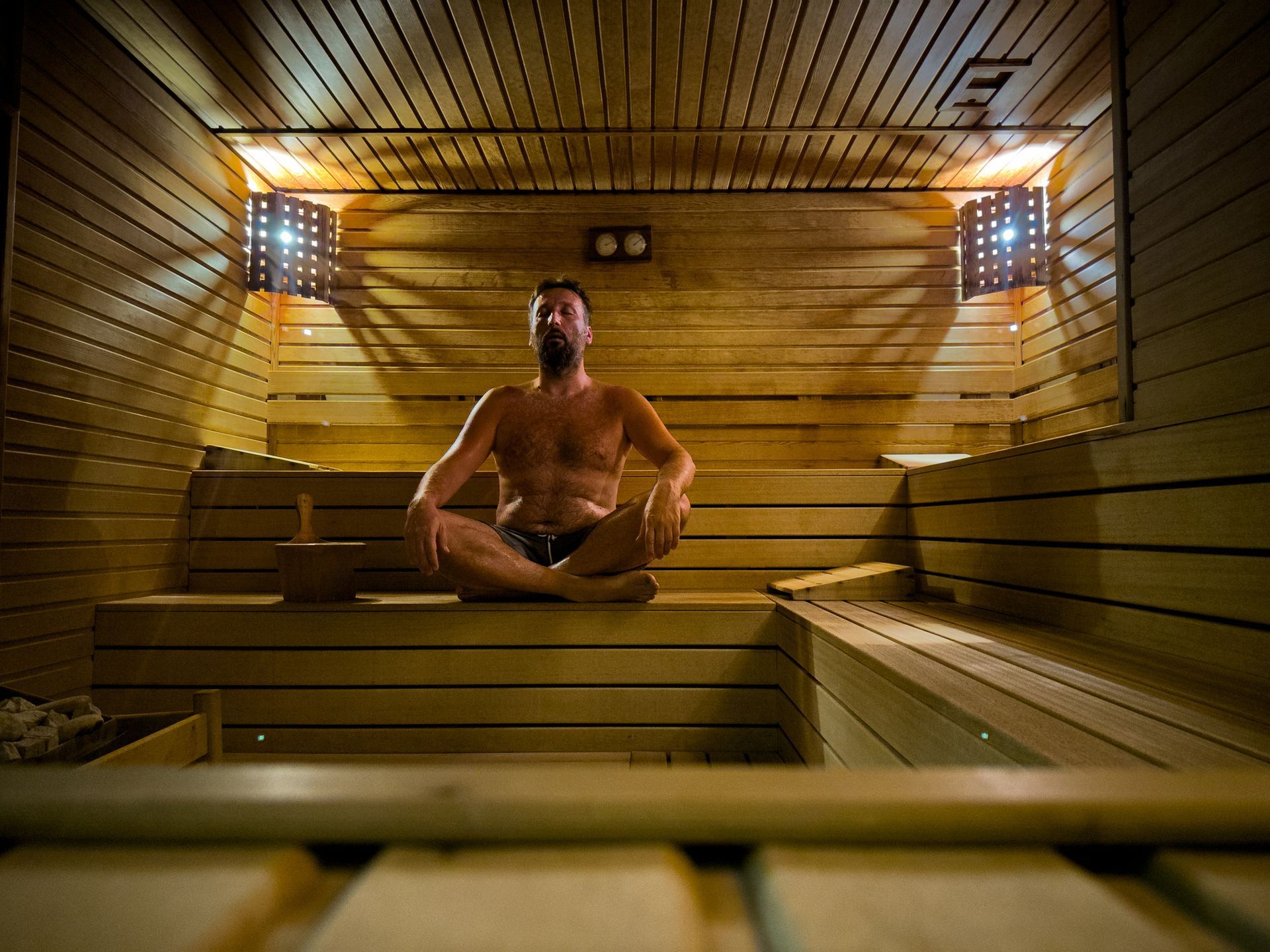 Un uomo è seduto in una sauna di legno con le gambe incrociate.