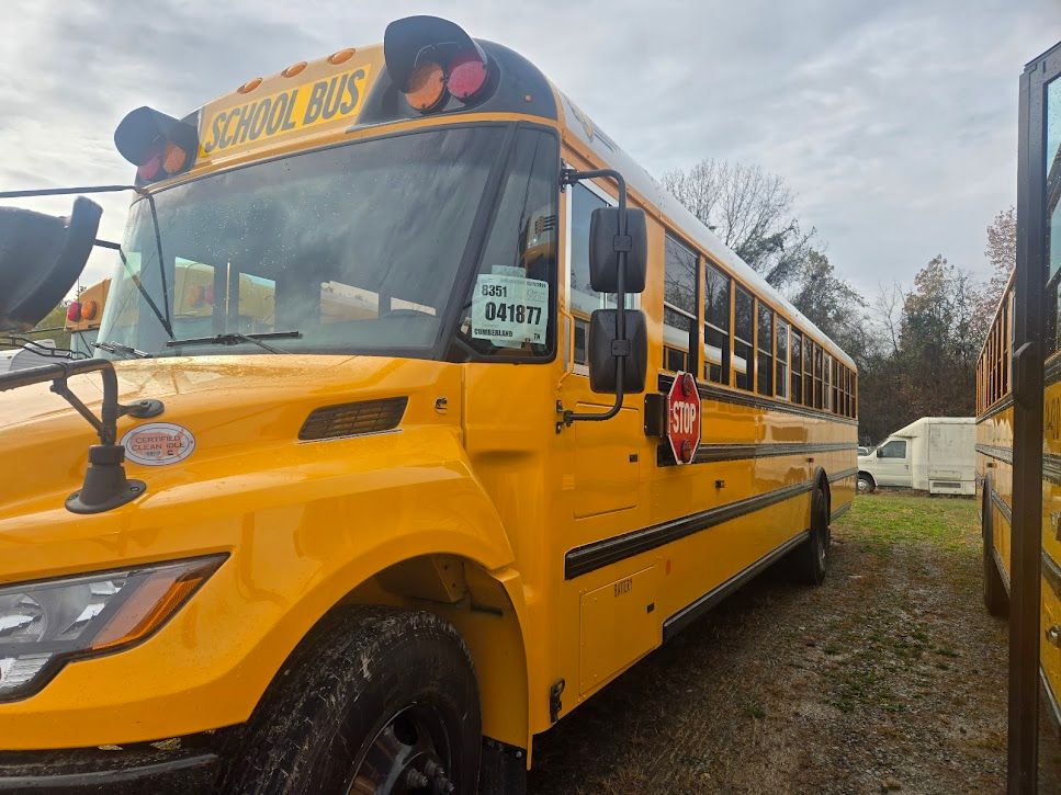A yellow school bus is parked in a field.