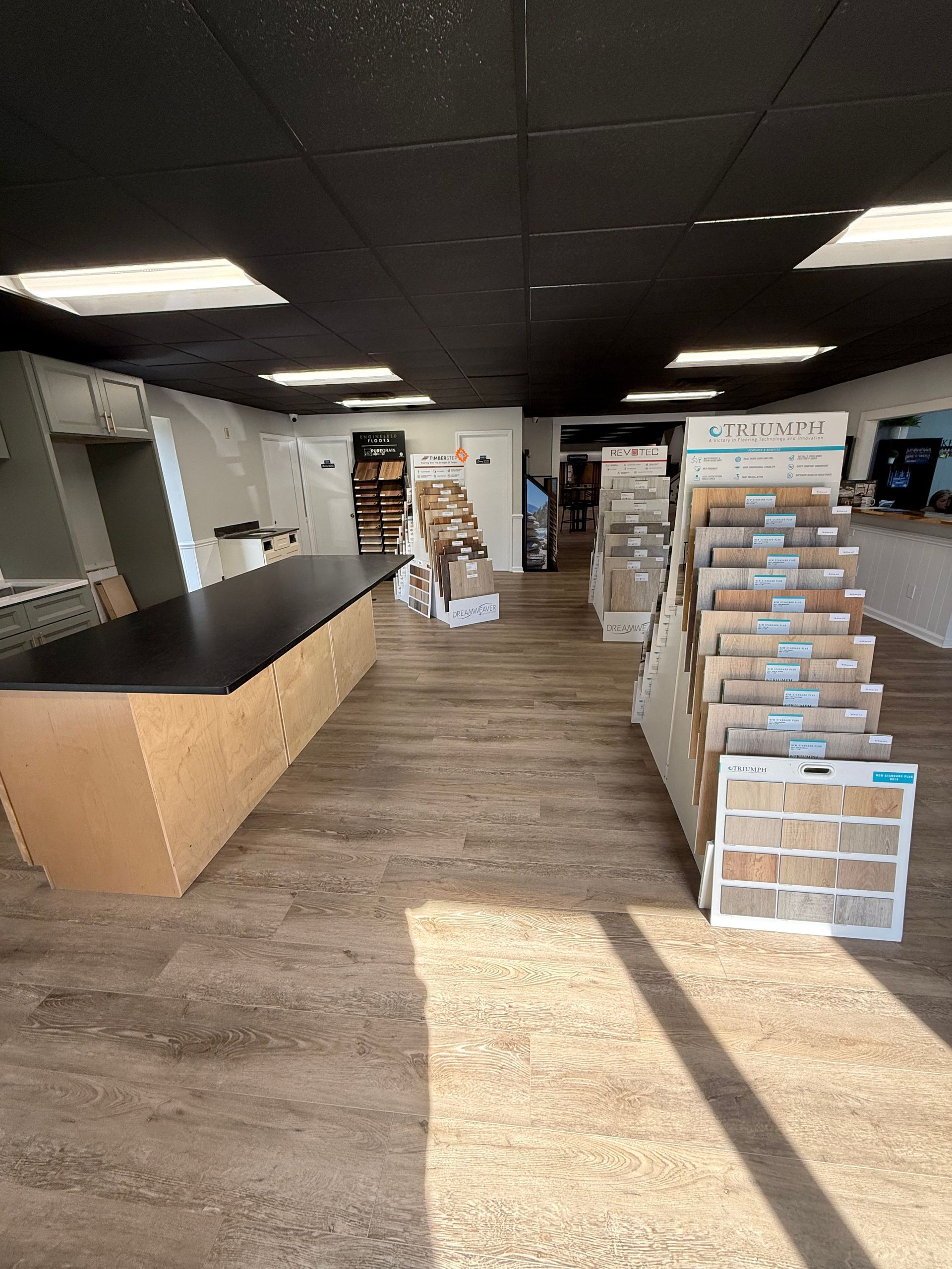 White kitchen with island, cabinets, countertops, stainless steel appliances, and wood flooring.
