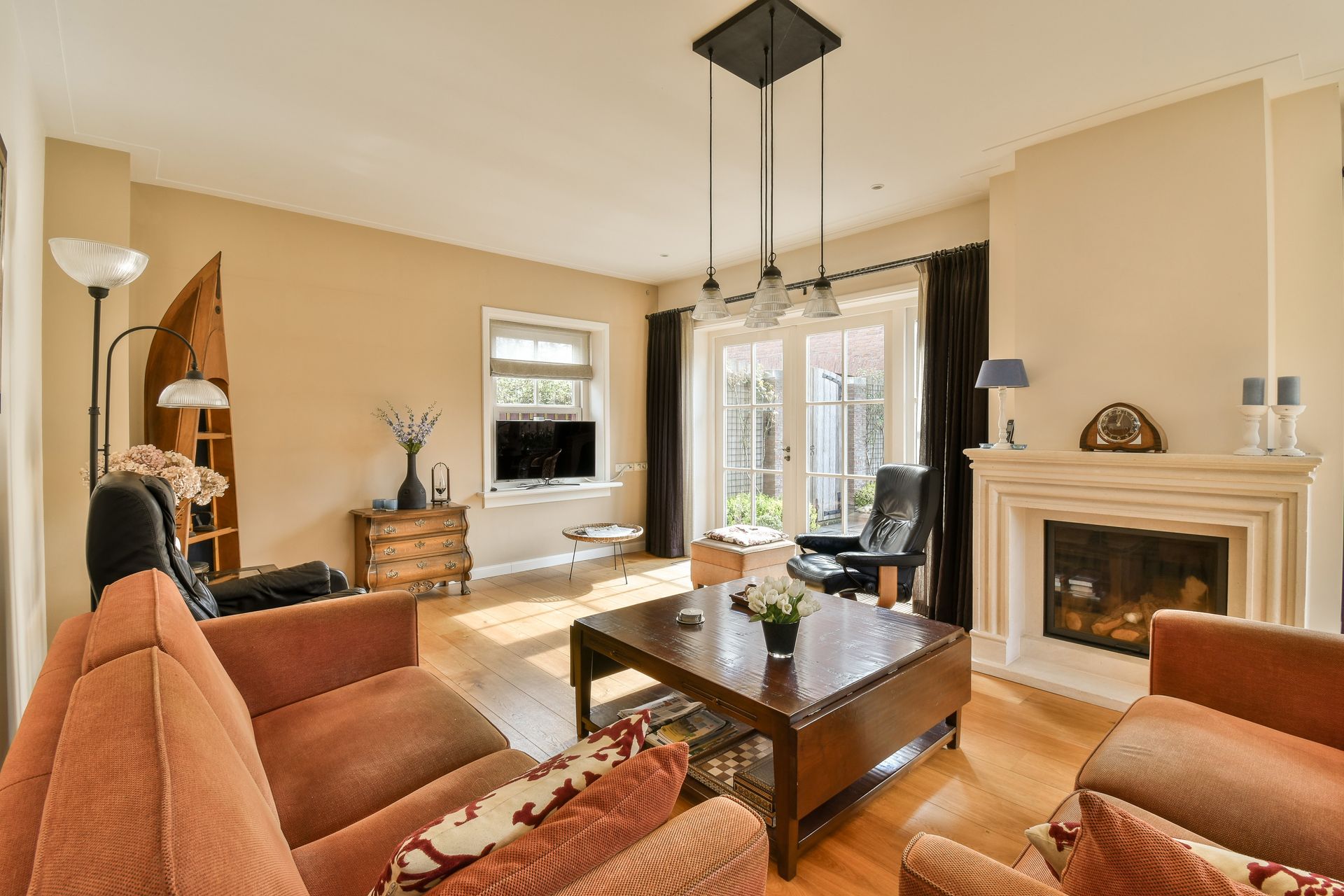 Cozy living room with a fireplace, sofa, chairs, a coffee table, and large windows.