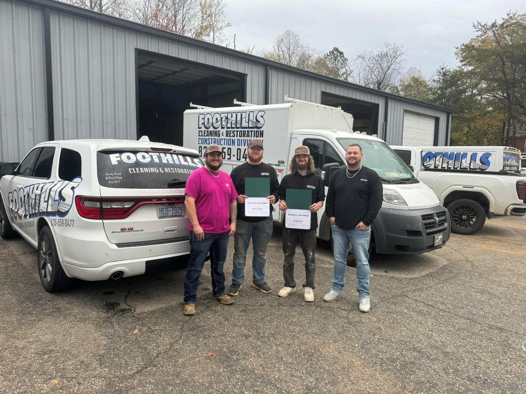 Four men stand by company vehicles, holding documents outside a building.