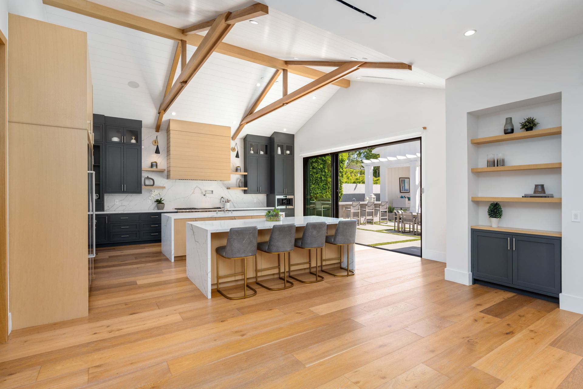 Modern kitchen with wood floors, gray cabinets, island seating, and open to a patio.
