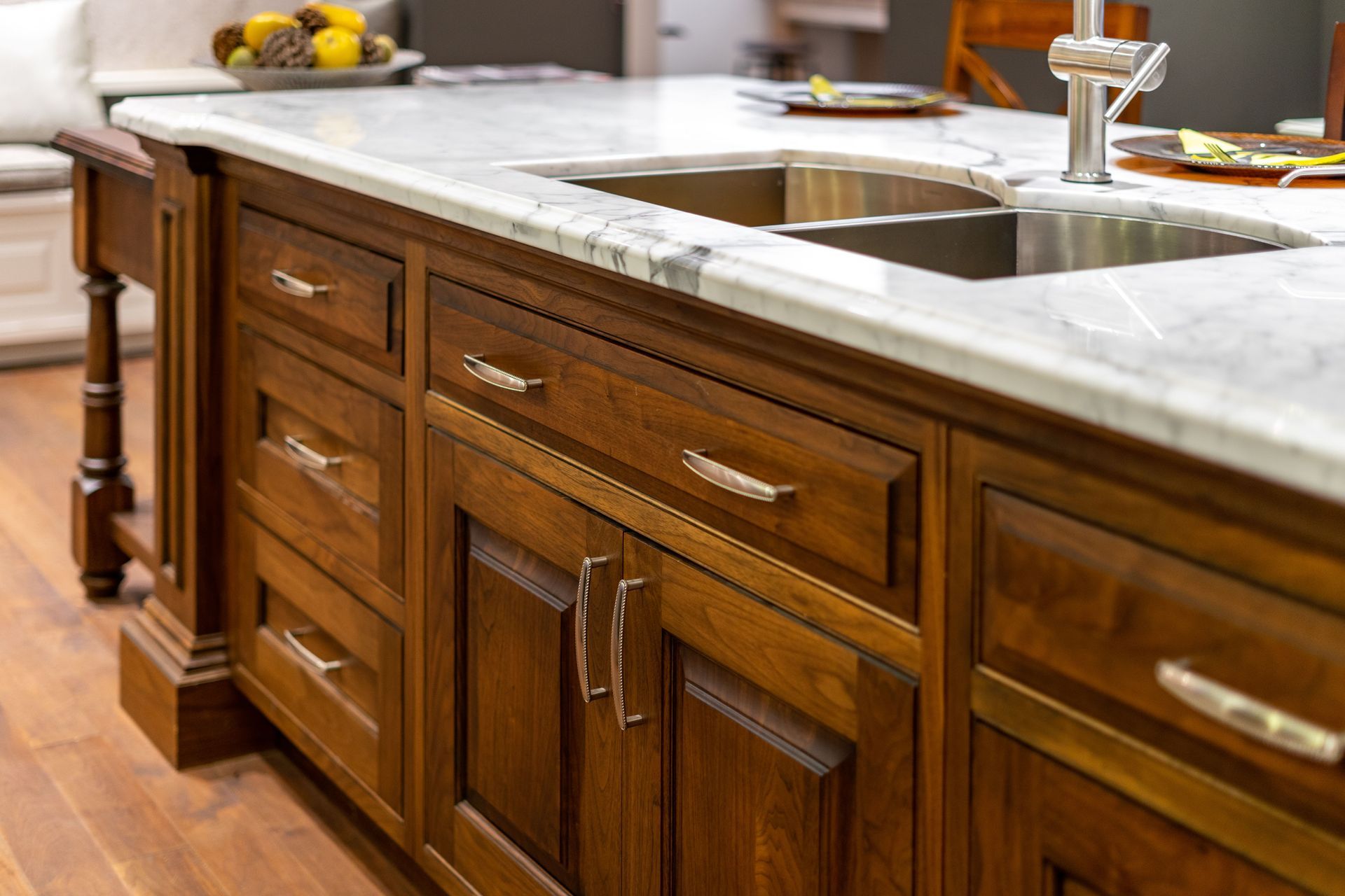 Wooden kitchen island with marble countertop, stainless steel sink, and drawers.