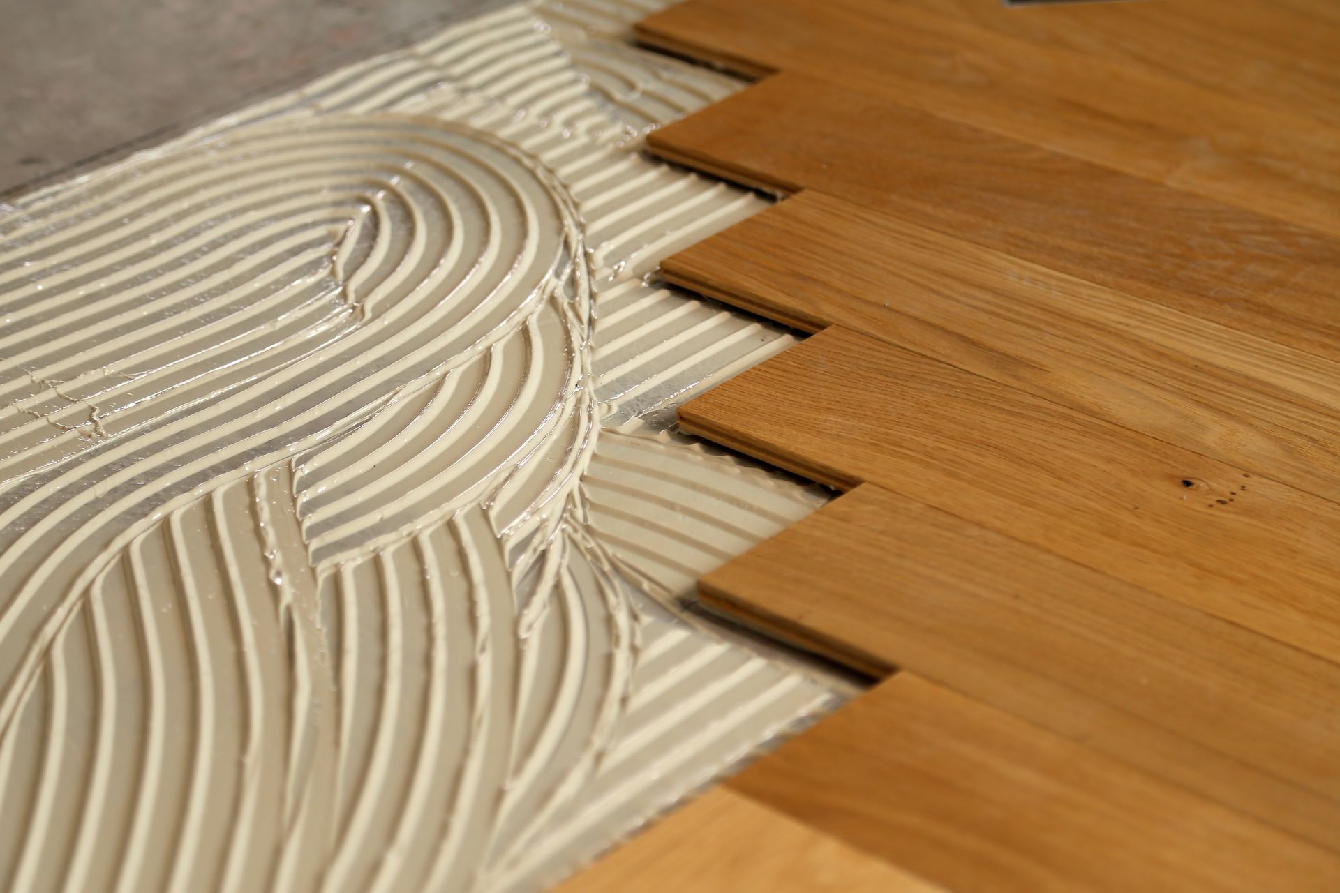 Wooden floorboards being installed with adhesive.