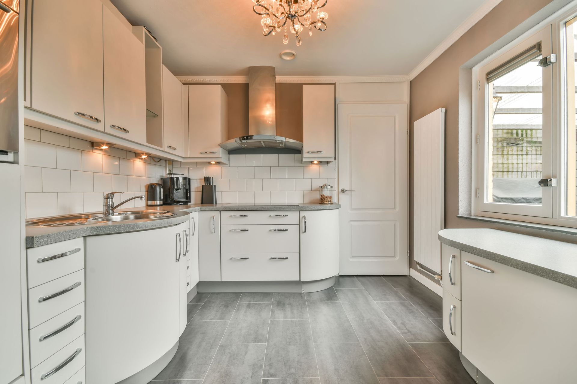 White kitchen with gray countertops, cabinets, and a stainless steel range hood.