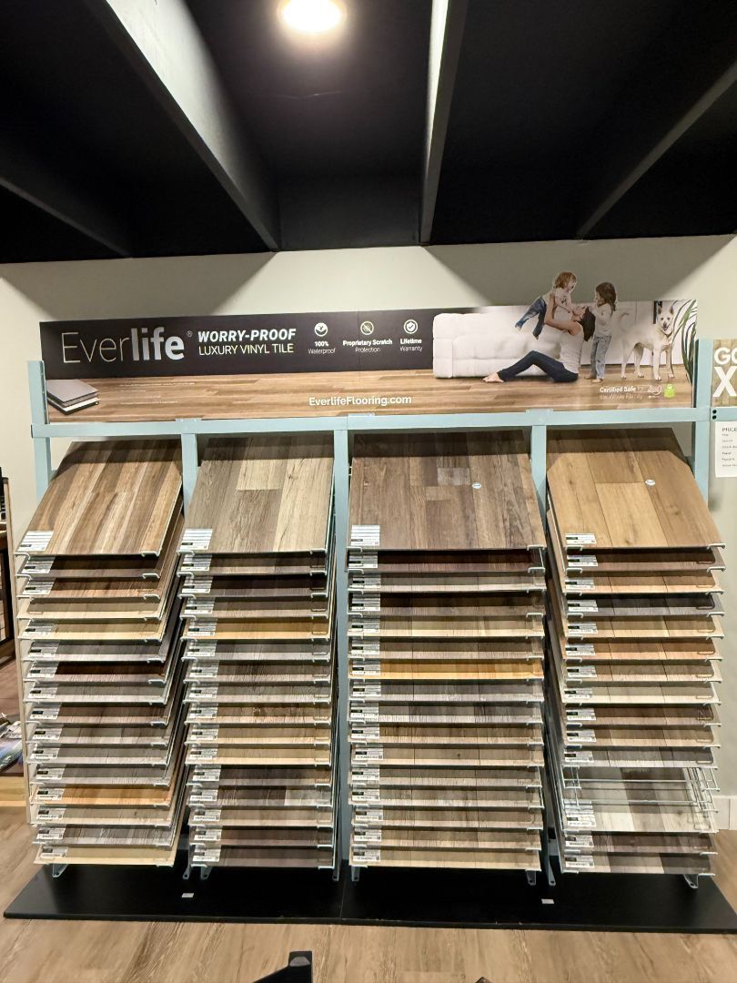Display of Everlife flooring samples, various wood-look patterns, arranged on racks in a retail setting.