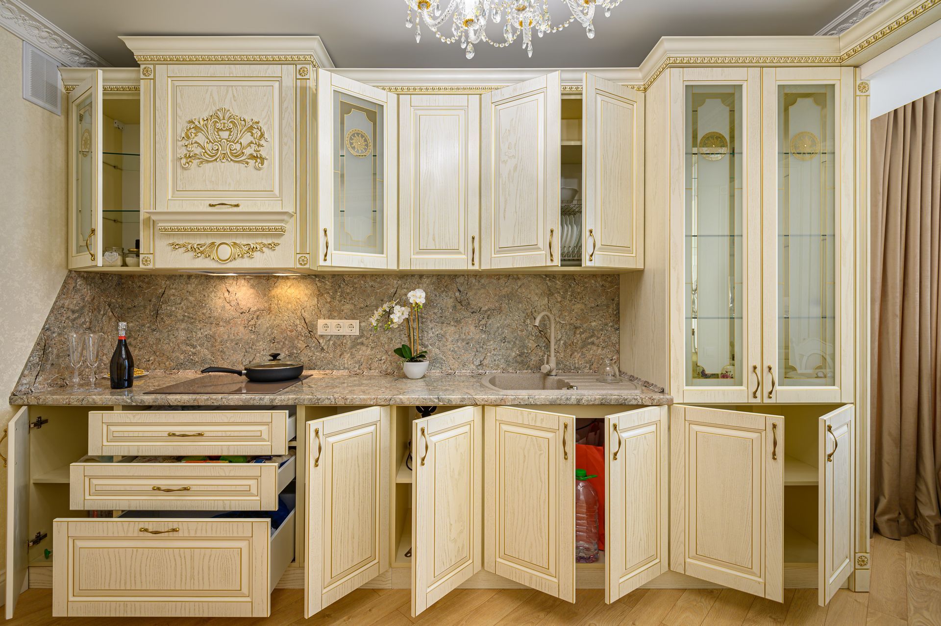 Cream-colored kitchen cabinets with open doors, granite countertop, and small appliances.