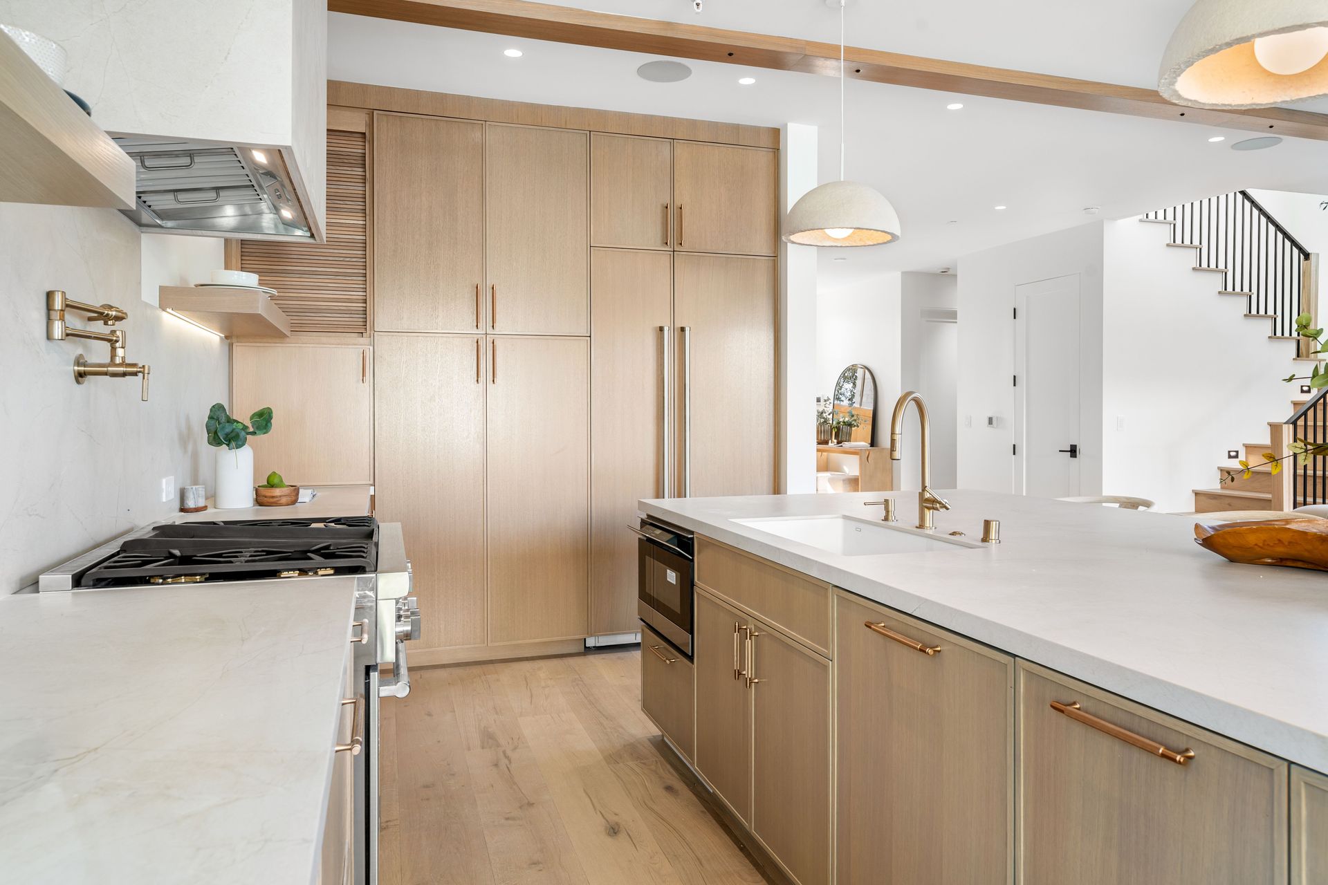 Modern kitchen with light wood cabinets, white countertops, and stainless steel appliances.