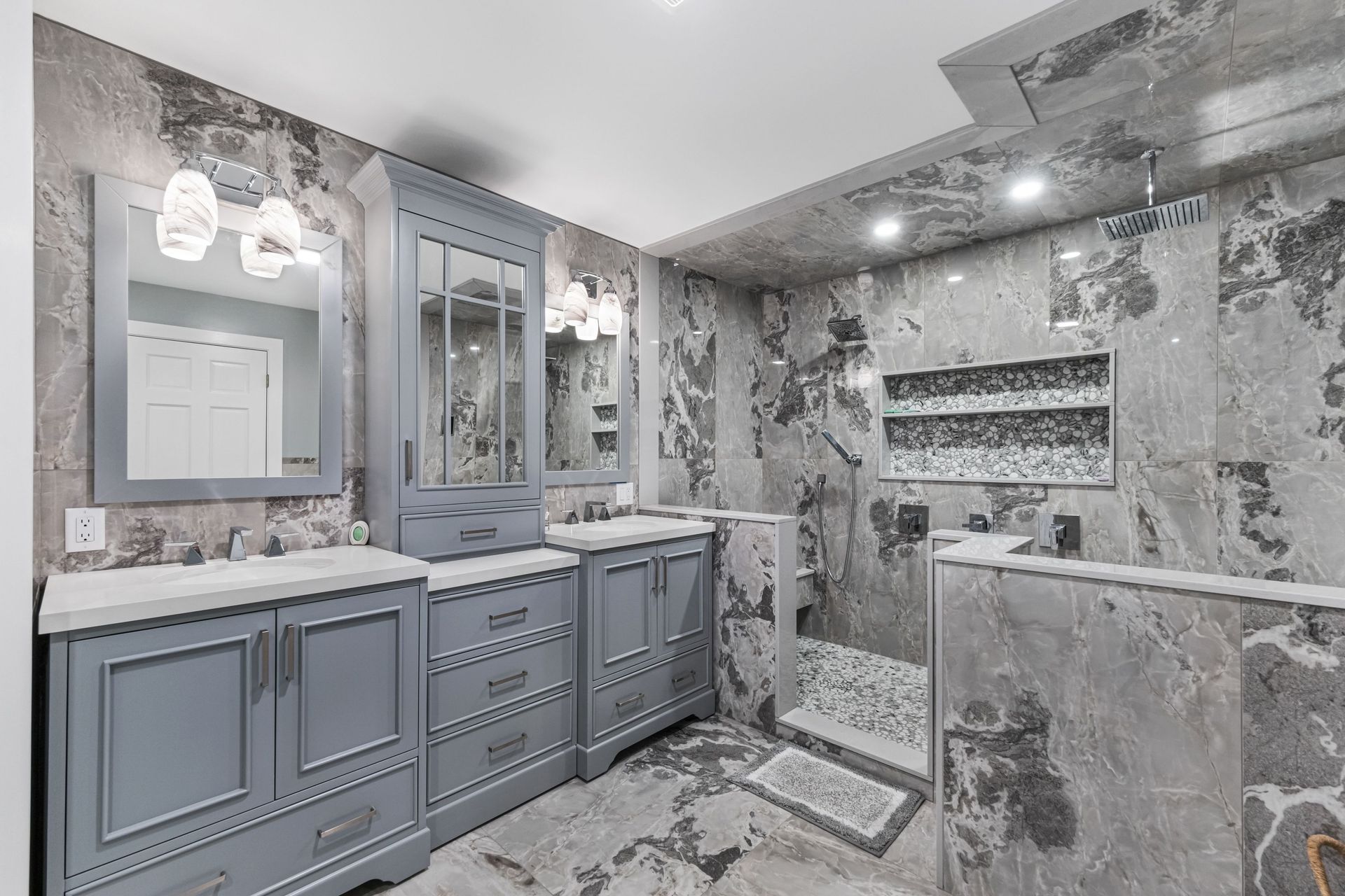 Gray and white bathroom with marble tile, gray cabinets, and a walk-in shower.