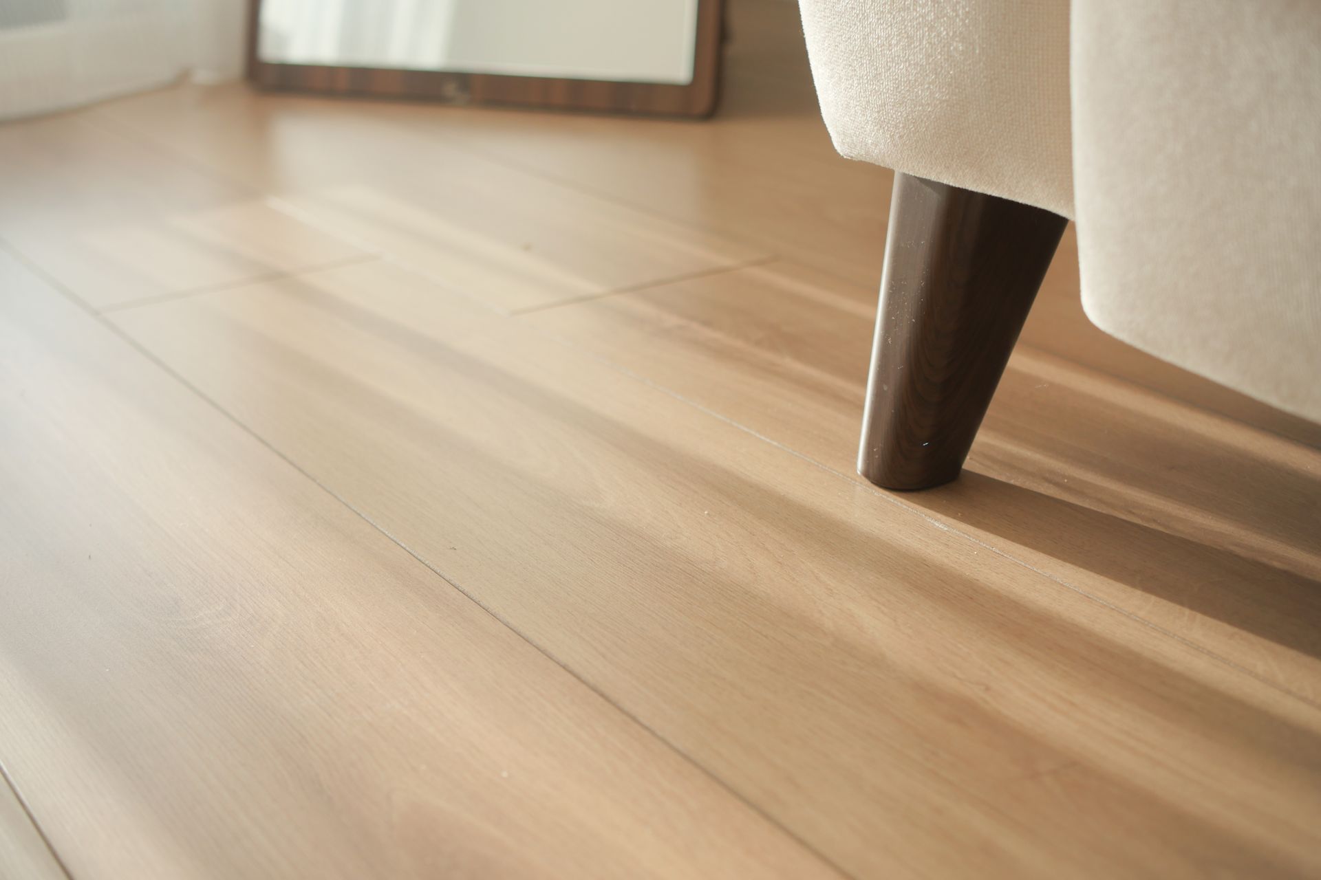 Wooden floor with sunlight and a furniture leg.