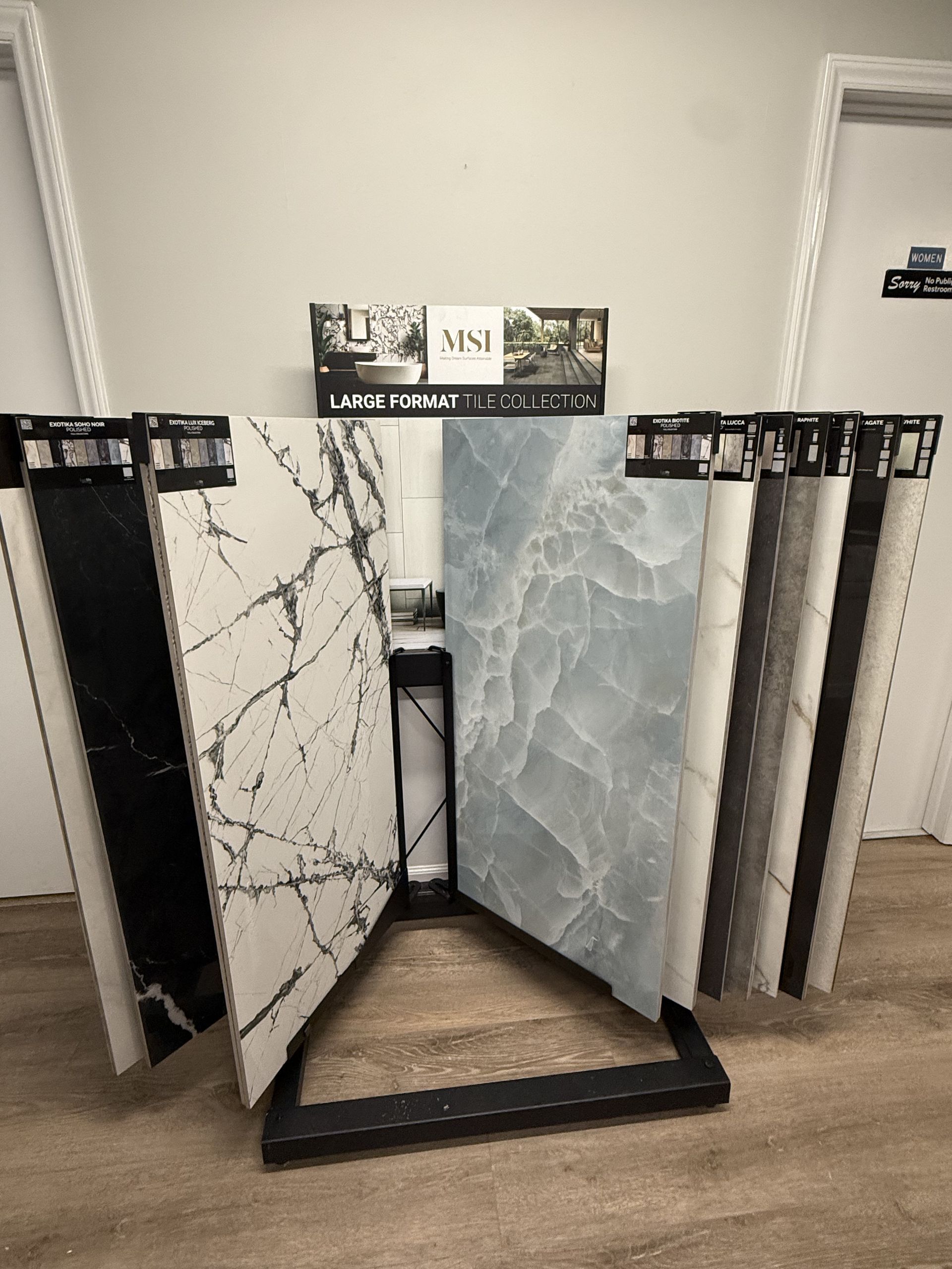 Tile samples displayed on a black rack, showcasing various patterns and colors.