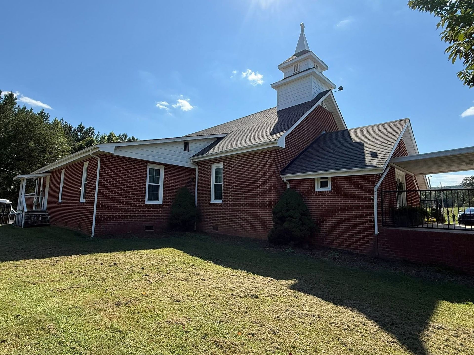 Modern white house with wood accents, surrounded by greenery and stone driveway.