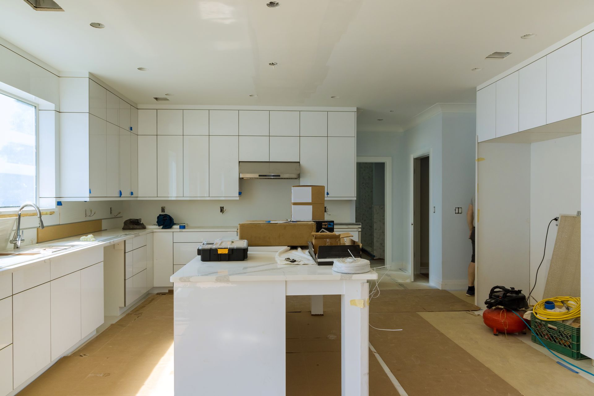 White kitchen under construction with cabinets and island.