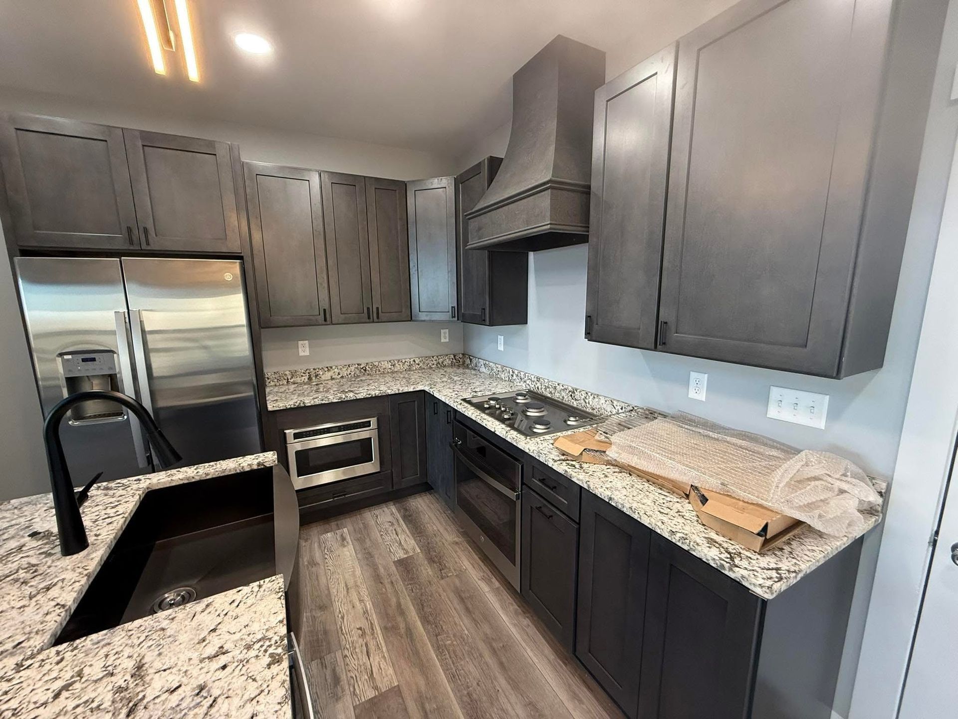 Gray kitchen with granite countertops, stainless steel appliances, and dark gray cabinets.