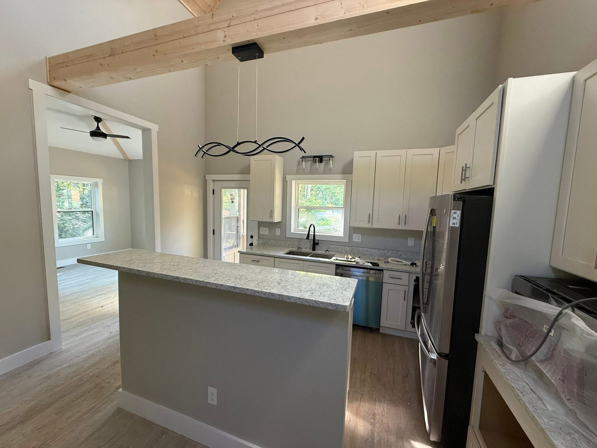 Kitchen with white cabinets, island, and stainless steel appliances. Light wood floor and open doorway.