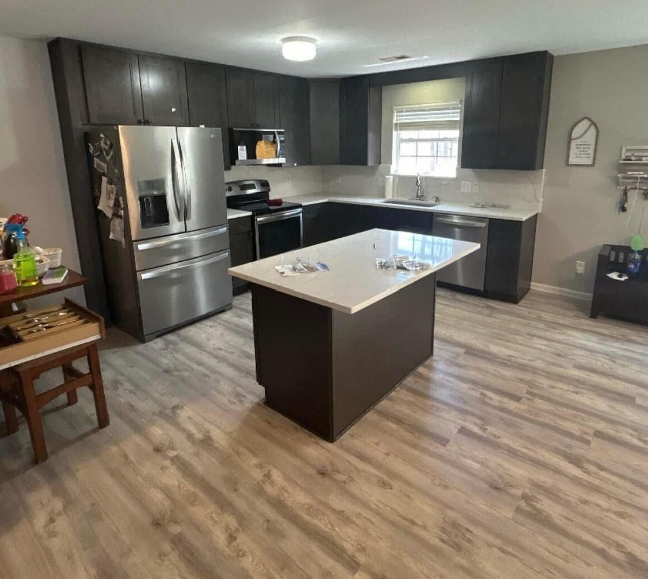Modern kitchen with dark brown cabinets, stainless steel appliances, and a white countertop island.
