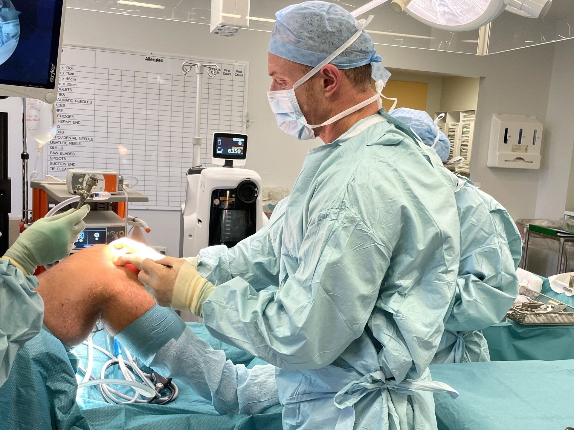 A knee surgeon is operating on a patient in an operating room.